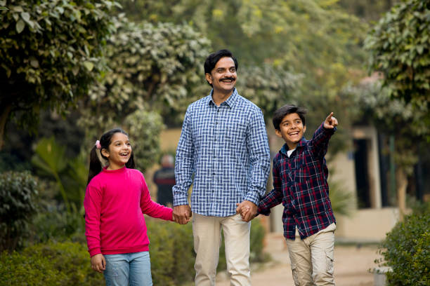 istock Happy father walking with children at park 1457682392