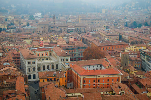 mystérieuse vue brumeuse en haute perspective depuis la tour du vieux centre-ville de bologne. vieux bâtiments avec des toits de tuiles rouges. lieu touristique célèbre et destination de voyage en europe. site du patrimoine mondial de l’unesco - smog city pollution town photos et images de collection