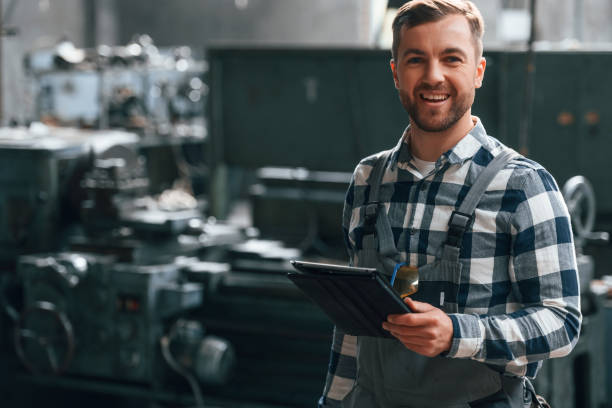 istock Standing and using graphic tablet. Factory male worker in uniform is indoors 1457684067