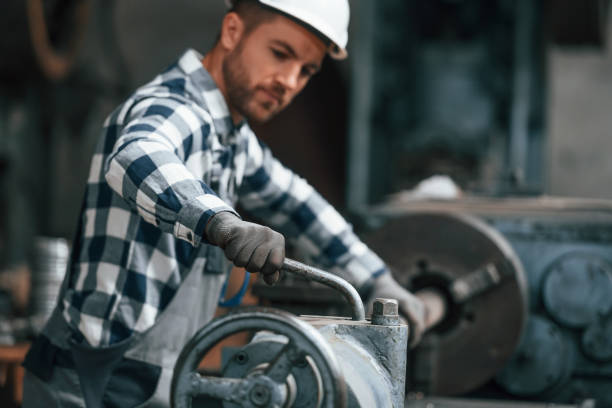 istock Working by operating machine. Factory worker in uniform is indoors 1457684154