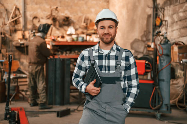 istock Many objects behind. Factory male worker in uniform is indoors 1457685477