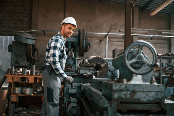 istock Side view. Operating the machine. Factory male worker in uniform is indoors 1457685596