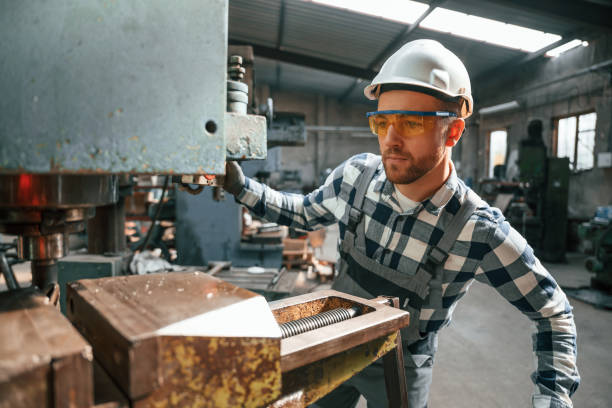 istock Factory male worker in uniform is indoors. Operating the drill machine 1457686508
