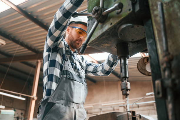 istock Factory male worker in uniform is indoors. Operating the drill machine 1457686582