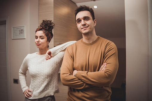 Portrait of young smiling man and woman couple hugging and standing in their living room