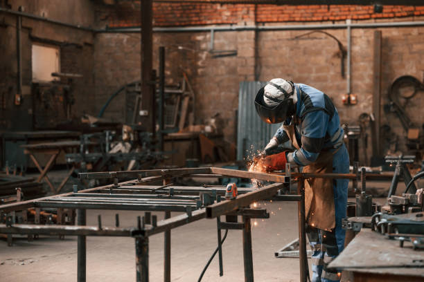 istock Factory worker in protective mask is welding the iron 1457687624