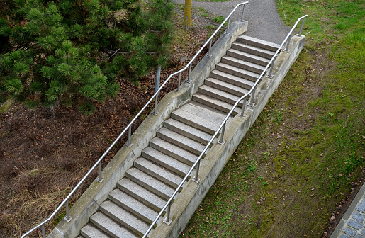 staircase with concrete sides at a public building. the safe staircase has two handrails, one with a reduced height for children under 12 at the entrance to the school, drone view, top, point of