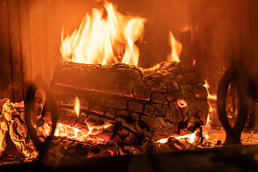 Log of wood burning in a fireplace inside a house, hearth