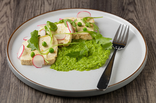 homemade vegan dish Miso tofu with peas and spring onion puree and sliced radish