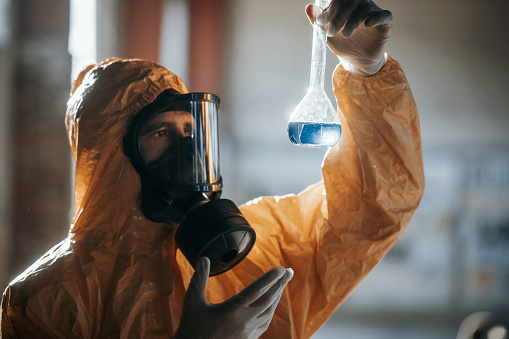 Portrait of a chemical plant worker wearing a gas mask and protective workwear while looking at the camera