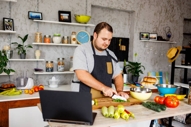 istock Overweight man chopping vegetables in the kitchen 1457690976