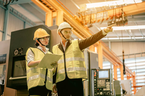 istock Male and female industrial engineers in hard hats discuss new project while using blue print in industry manufacturing factory.Engineer and Architect  concept. 1457691431