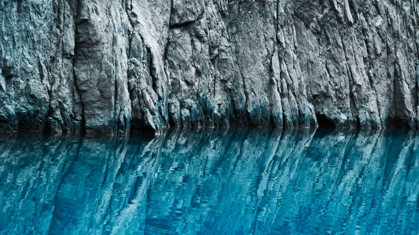 Rock formation in the reflection of blue water. Nature background. Selective focus.