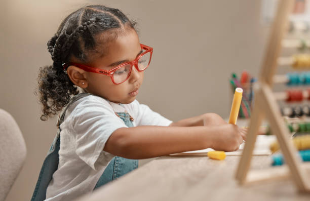 istock Home learning, education and girl in kindergarten studying math and knowledge development. House, student and assessment focus and writing of a child working on numbers for a study test  at a desk 1457693554