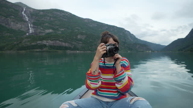 Woman photographing while canoeing on the lake in Norway