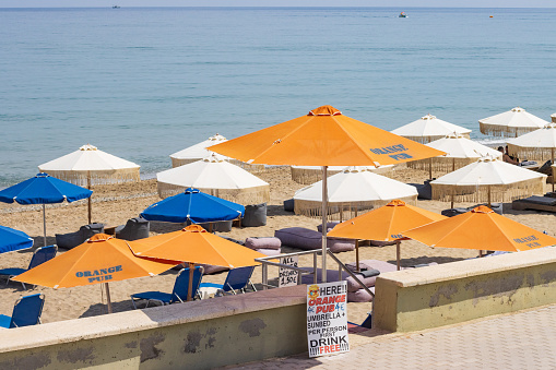 Commercial sign advertising Orange Pub Sunbed Hire on Urban Beach at Rethymnon on Crete, Greece