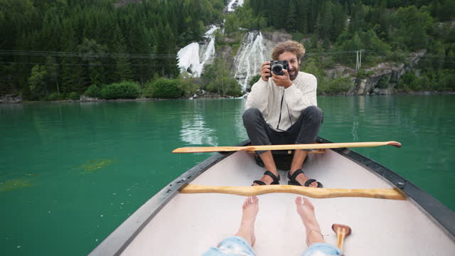Man photographing while canoeing on the lake in Norway