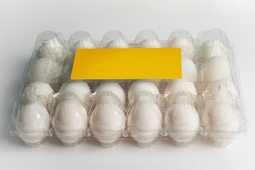 A plastic carton of 2 dozen eggs with a blank yellow label.