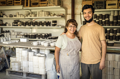 Wife and son smiling and looking at the camera in the ceramics studio. Family business.
