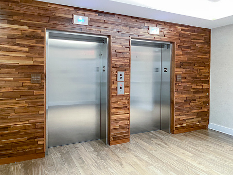 Closed metalic modern elevator door with green color frame in modern business office building.
