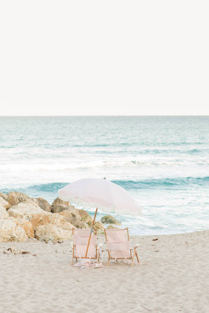 istock Boho Striped Pink & White Beach Umbrella & Folding Beach Chairs on Palm Beach, Florida at Sunset 1457702830