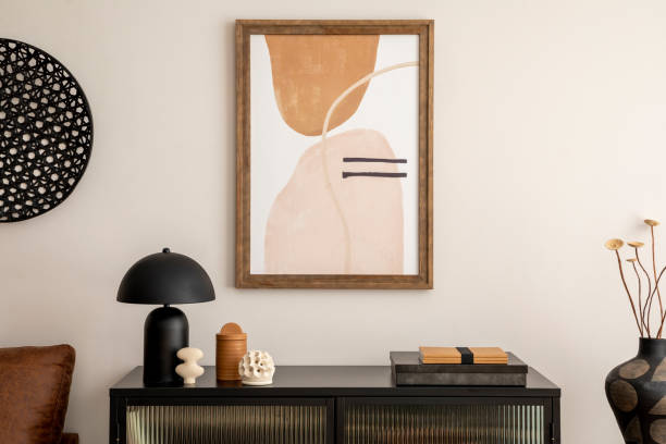 istock Creative composition of living room interior with mock up poster frame, black commode, lamp, decoration on the wall, books and elegant personal accessories. Home decor. Template. 1457704356