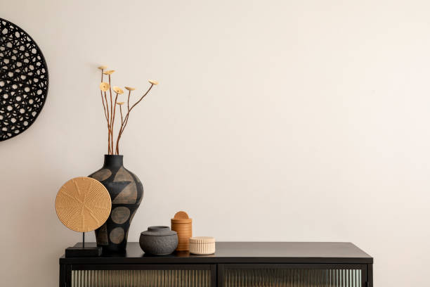 istock Minimalist composition of living room interior with copy space, black commode, vase with dried flowers, decoration on the wall and stylish personal accessories. Home decor. Template. 1457704381
