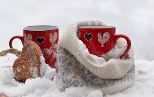 istock two red mugs with heart shaped one in a woolen hat  on the snow 1457710796