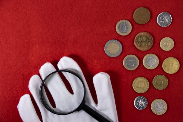 istock Expert gloves and magnifying glass with coins on red cloth, space for text top view, copy space 1457713157