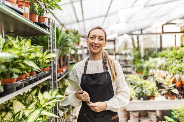 istock Young florist working in greenhouse holding digital tablet 1457713364
