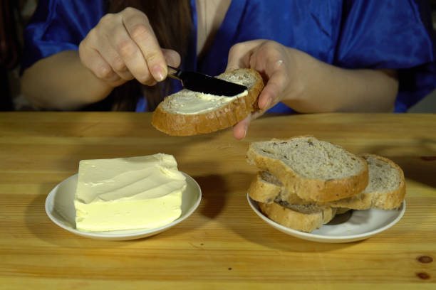 istock Young woman preparing a sandwich, spreads butter on bread. 1457715358