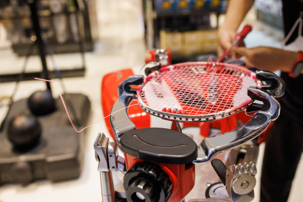 バドミントンラケットを織る、ラケット織り機でバドミントンラケットをひもでつなぐ。スポーツサービスショップでバドミントンネットを修理します。 - racket string ストックフォトと画像