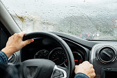 Senior woman driver driving her car on a rainy day. Elderly woman holding the steering wheel as she operates the wiper stalk