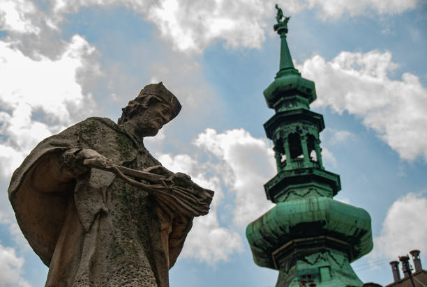 A low-angle statue of a man with a tower beside him in Bratislava, Slovakia