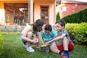 Children sharing a basket of Easter eggs in a garden