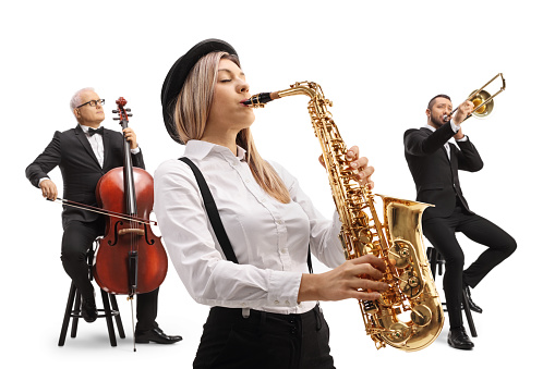 Woman playing a sax and two men in the back playing a trombone and a cello isolated on white background