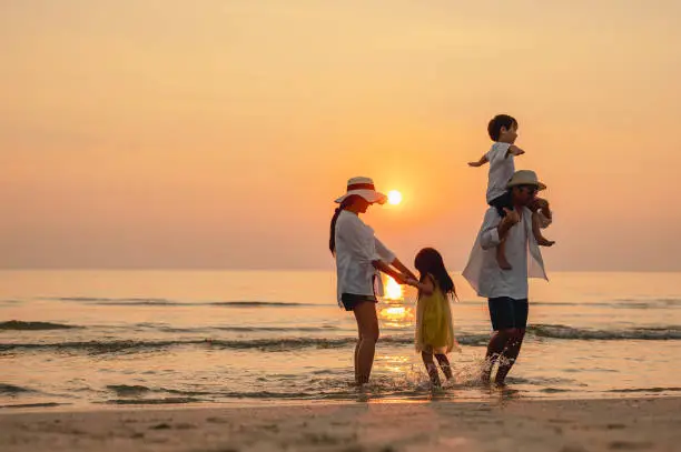 Photo of Happy asian family that enjoys beach activities during the summer holidays. parent and children enjoy the sunset sea on beach.Holiday travel concept, Summer vacations.