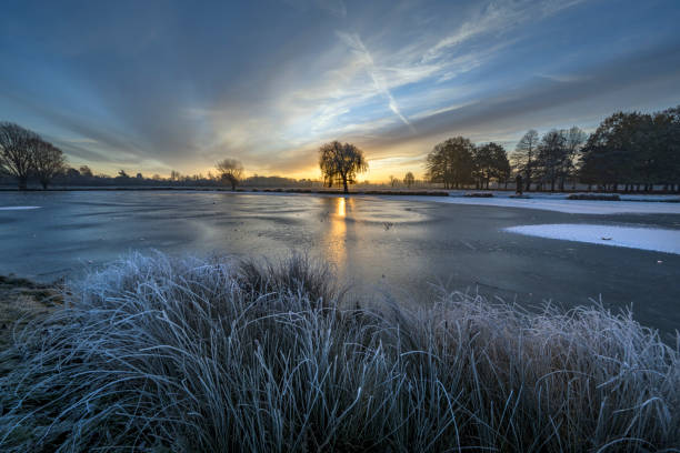 Rising sun over the blue frozen ice at Bushy Park ponds in Surrey England