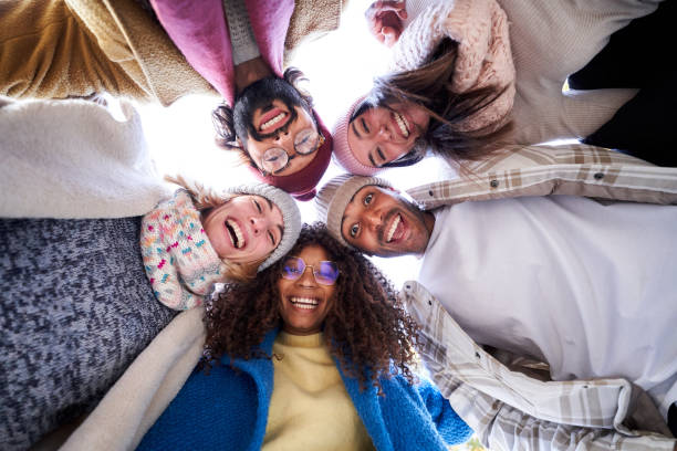 istock Multiracial group of happy friends doing a circle embracing, looking down to the camera cheerfully. 1457725128