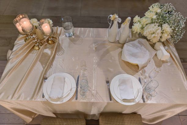 istock Festive table with arch decorated composition flowers, candles in hall restaurant. Table newlyweds covered with a tablecloth in banquet area on wedding party. Table setting, reception. Top view. 1457726542