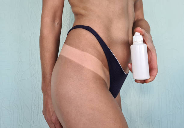 женские ноги после автозагара и крема с флаконом - spray tan body human skin стоковые фото и изображения
