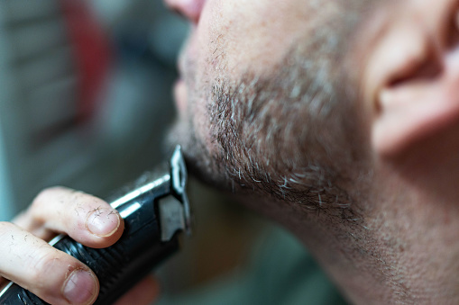 Man using electric razor for shaving his beard