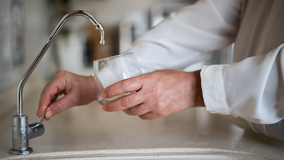 Close-up Adult woman filling water from the tap in the kitchen