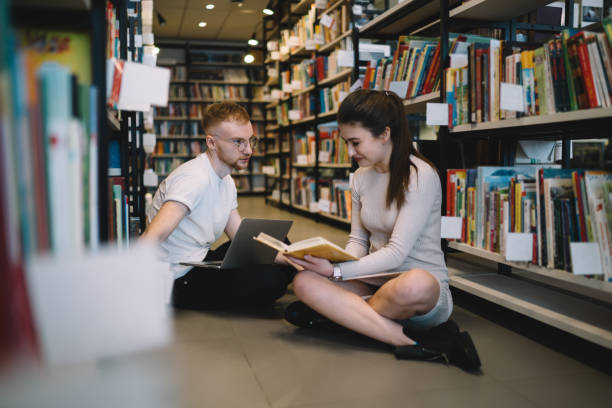 istock Glad female student smiling while reading funny story 1457738454