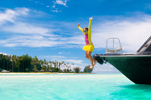 Kids jump into sea. Yacht vacation with child on exotic tropical island with crystal clear water. Beach and swim fun. Sailing and cruise with children. Summer holiday on boat. Little boy swimming.