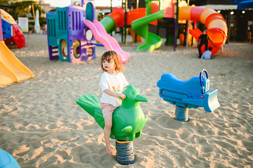 little girl playing on a beach outdoor playground.