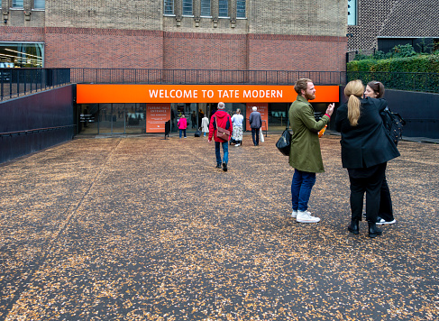 Art-lovers approaching and standing outside, the Turbine Hall entrance to Tate Modern, the famous modern art gallery on London’s South Bank.