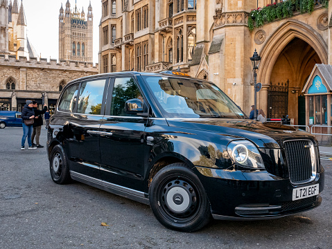 A few tourists and a very shiny black taxi waiting outside Westminster Abbey in Central London.