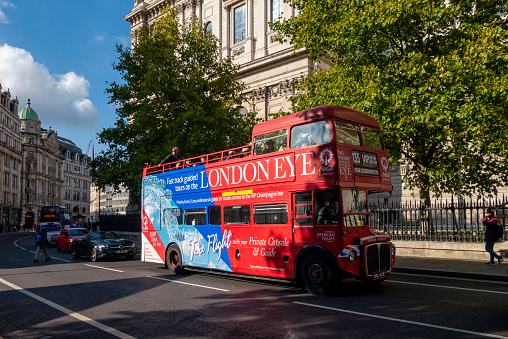 An old red double decker Routemaster bus in use as a London Eye tourbus, passing St Paul’s Cathedral in the City of London.