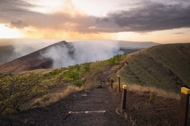 Hiking path in volcano crater Hiking path in volcano crater with smoke going up on sunset light time masaya volcano stock pictures, royalty-free photos & images